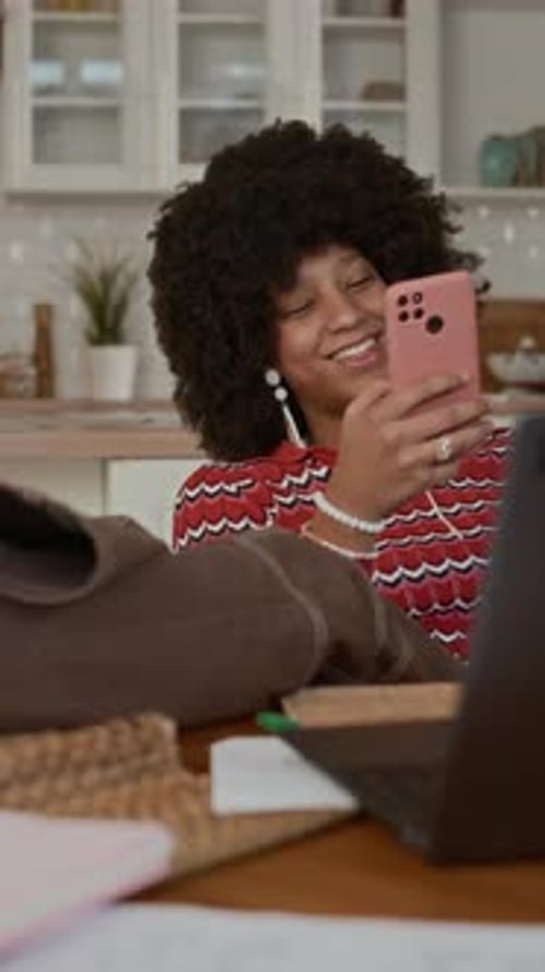 Smiling Woman Using Phone and Laptop at Home