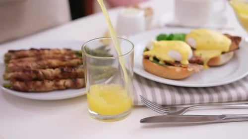 Pouring Juice With Eggs Benedict and Asparagus