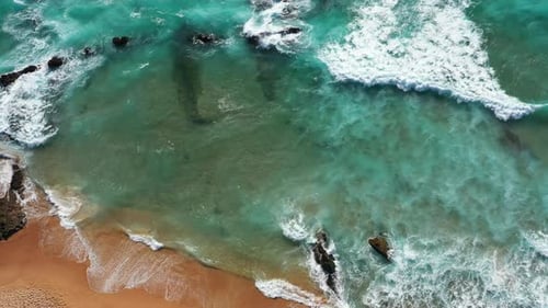 Drone View of Serene Ocean Waves Moving Towards Shore Through Rocks