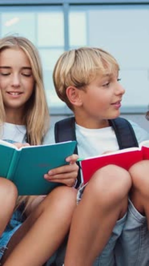 Nahaufnahme von vier kaukasischen Schulfreunden, die reden und Hausaufgaben machen und Spaß beim Pausensitzen haben