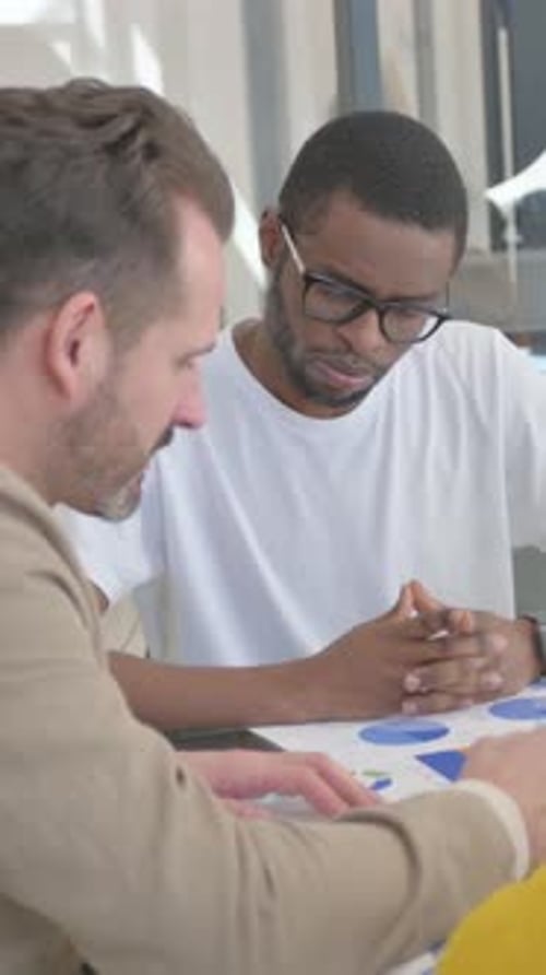 Men Discussing Charts at Desk in Office