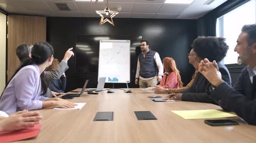 Businessman Explaining Strategy on Whiteboard to Diverse Colleagues in Office