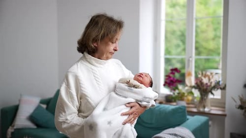Senior Woman Holds Newborn Baby Wrapped in Blanket