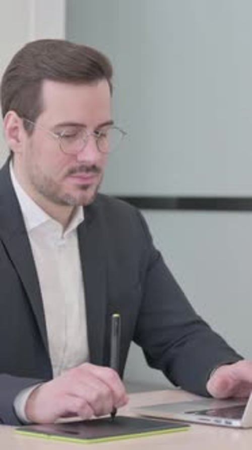 Kaukasischer Designer arbeitet an Laptop und Grafiktablett, vertikales Video