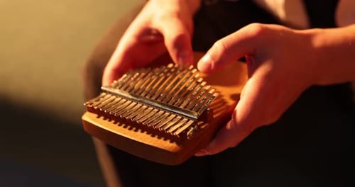 Hombre jugando a la kalimba en el sofá de su casa, de cerca. Cámara moviéndose hacia la izquierda