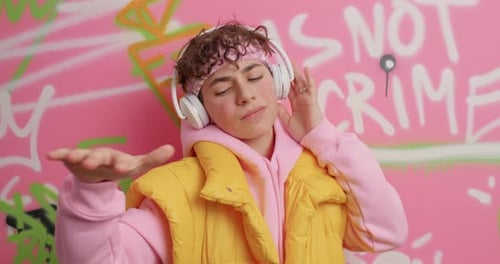 Man with Headphones Dancing near Graffiti Wall