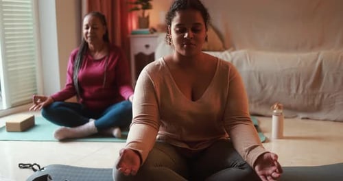 Two Women Meditate Indoors on Yoga Mats