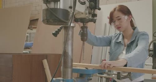 Worker young woman carpenter building design and drilling wooden