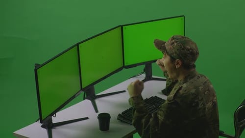 Side View Of Man Soldier Celebrating While Working With Mock Up Multiple Monitor In Green Screen