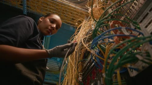 Woman Works on Cable Connections in Server Room