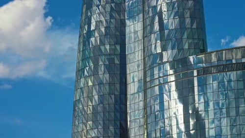 Urban Glass Skyscraper Reflecting Sunlit Clouds With Distinctive Geometric Patterns And Sleek