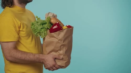 Closeup Shot Female Customer Takes Paper Bag Full of Grocery Products From a Delivery Man in Yellow