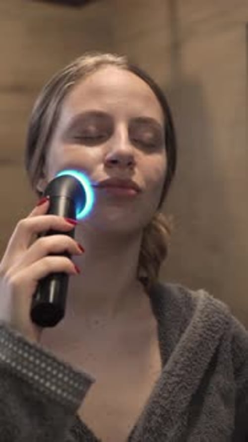 Woman Uses Light Therapy Device on Face