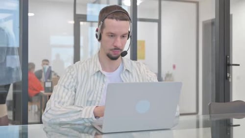 Young Man Working on Laptop in Modern Office