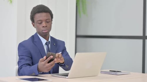 Young Man Working at Desk With Phone and Laptop