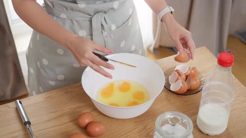 Woman Cracking Eggs Into Bowl For Baking
