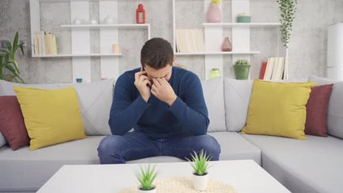 Man Upset and on Phone on Sofa Indoors