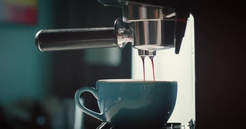 Pouring a Stream of Coffee From a Machine Into a Blue Cup Homemade Hot Espresso Using a Filter