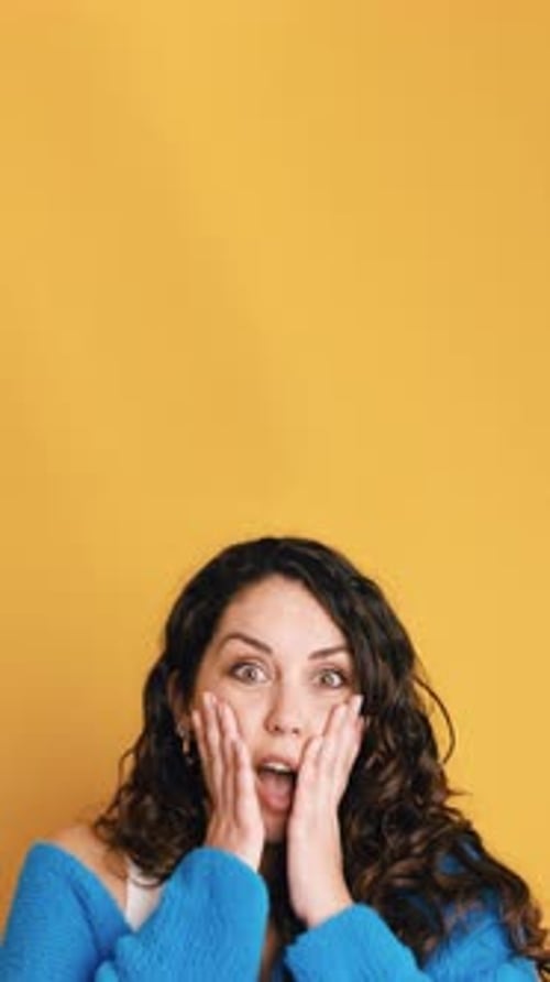 Surprised Woman with Hands on Face on Yellow
