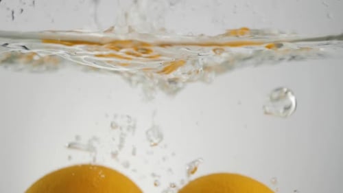 Two Oranges Dropped into Clear Water