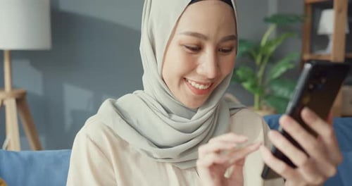 Smiling Woman Using Smartphone Indoors on Sofa