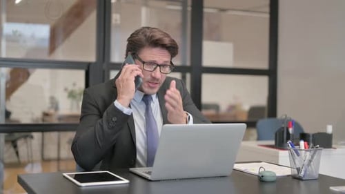 Man in Suit Talking on the Phone at Desk