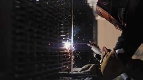 Welder Working on Metal Grate at Night