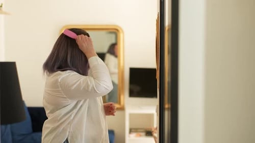 Side View of Young Overweight Combing Her Hair in Front of the Mirror Standing at Mirror in