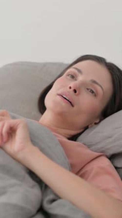 Woman Resting Comfortably Under Blanket in Bed