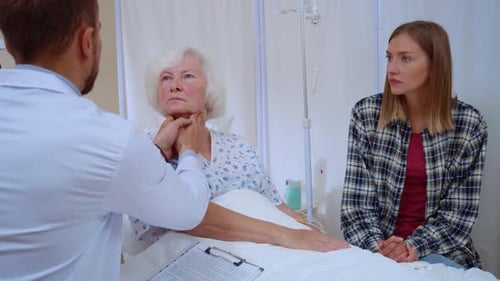 Doctor Examining Senior Patient with Family in Hospital Room