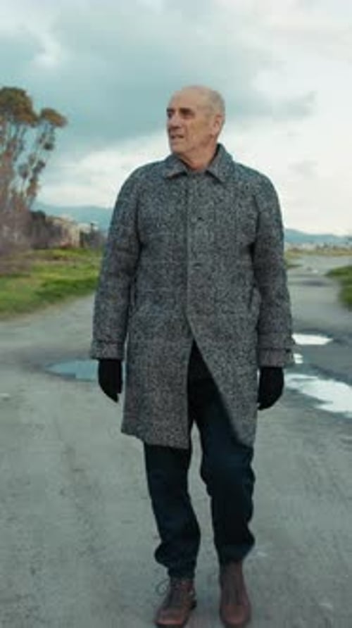 Elderly Man Walking on a Dirt Road During Winter