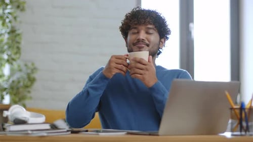 Young Man Enjoying Coffee Break from Laptop