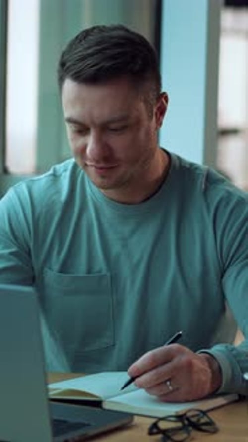 Young Adult Uses Laptop and Notebook Indoors