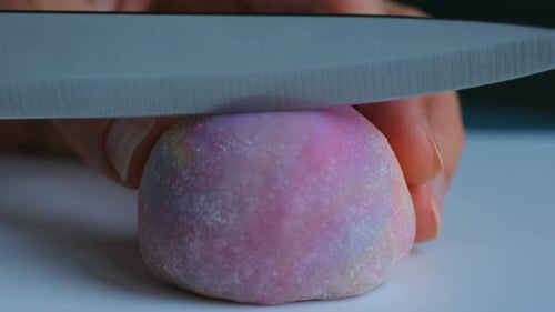 Frau schneidet den lila Mochi-Kuchen vorsichtig mit Messer durch