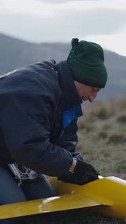 Man Repairing Remote Controlled Airplane in Field