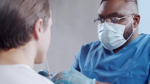 Afroamerikanischer Arzt führt im Krankenhausbüro einen Coronavirus-Test durch: Mediziner und Patient