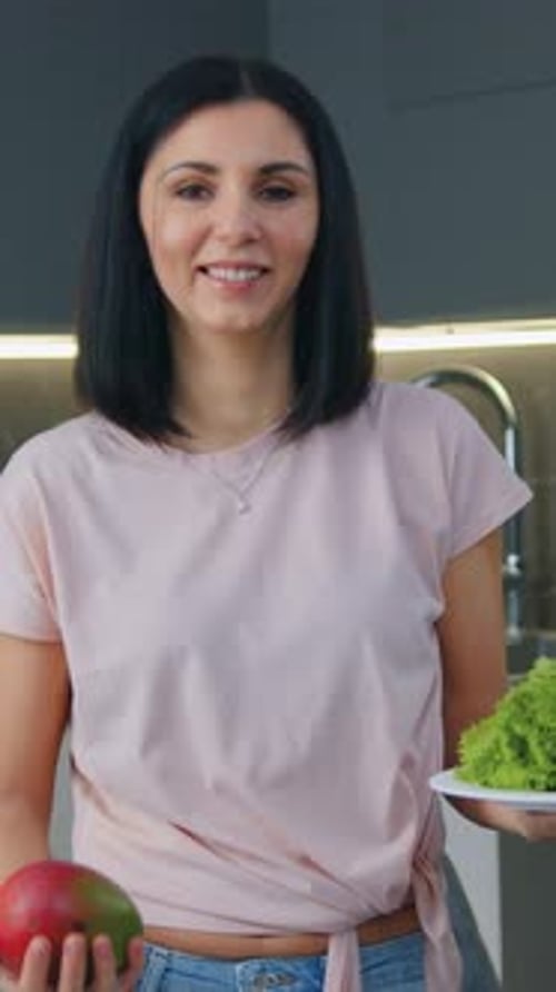 Portrait d'une belle femme de 30 ans, positive et satisfaite, tenant une assiette avec des feuilles de laitue en une