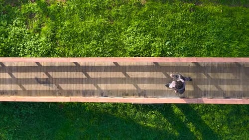 Overhead View Of A Man Walking On Wooden Bridge. - aerial shot