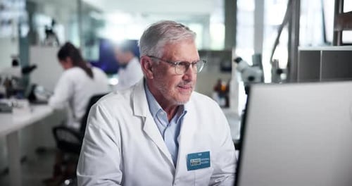 Senior Scientist Smiles at Computer in Bright Lab