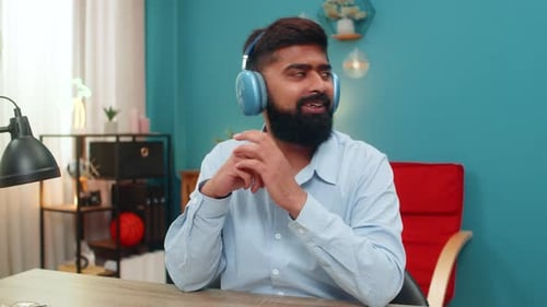 Man with Headphones Gesturing While Sitting at Desk