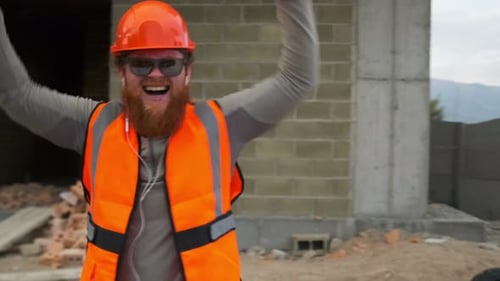 Trabalhador da construção civil dançando de perto ouve música em fones de ouvido, canteiro de obras