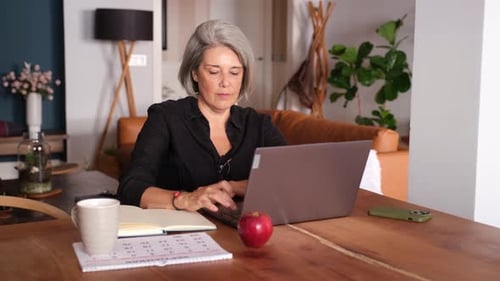 Focused businesswoman working from home, writing and typing on laptop