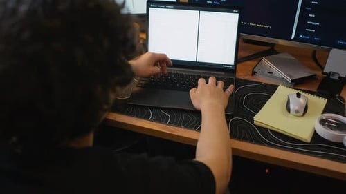 Man Software Developer Typing Code on Laptop at Workstation