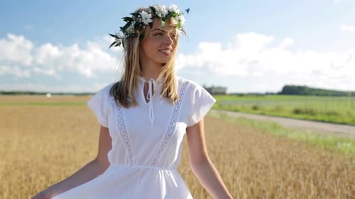 Smiling woman with flower crown walks through wheat field