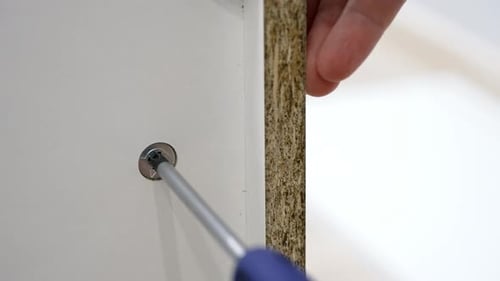 Carpenter tightening screw on white furniture panel