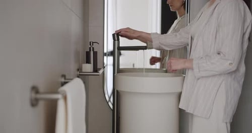 Woman Washing Hands in Modern Bathroom Sink