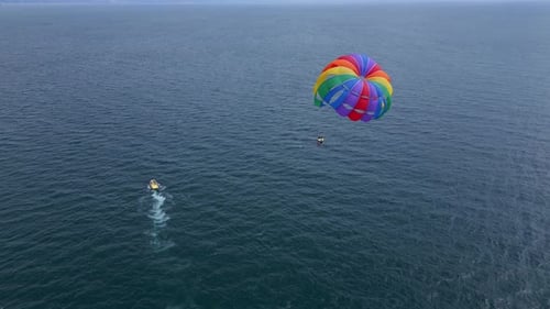 Drone Video of a Colorful Parasail Soaring Over the Open Ocean Towed By a Speedboat Below The Aerial