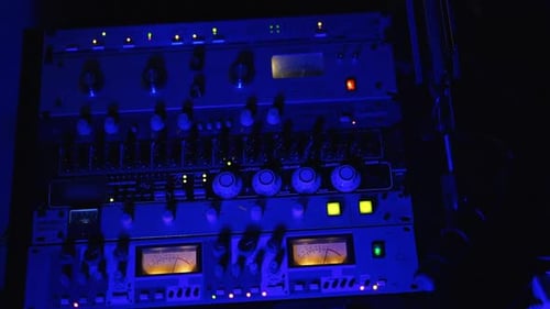 Soundboard mixer switched on in dark recording studio.