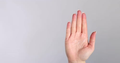 Woman's Hand Clenches into a Fist on Grey Background