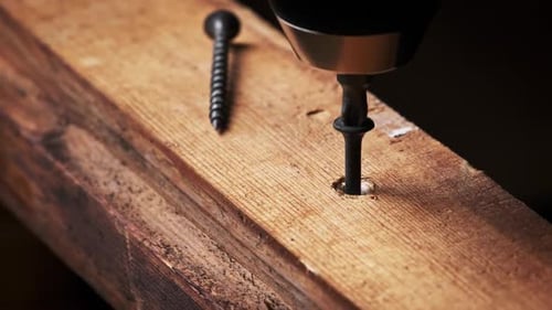 CloseUp of Screw is Unscrewed From a Wood Board with a Screwdriver